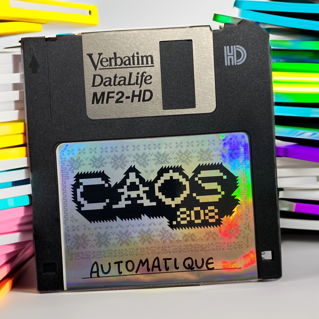 Holographic label of the CAOS.808 logo on a Verbatim floppy disk, featuring neon colors and pixelated design.