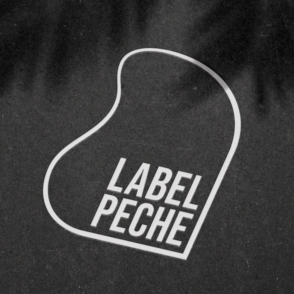  Embossed Label Pêche logo on a black background, featuring minimalist organic shapes.